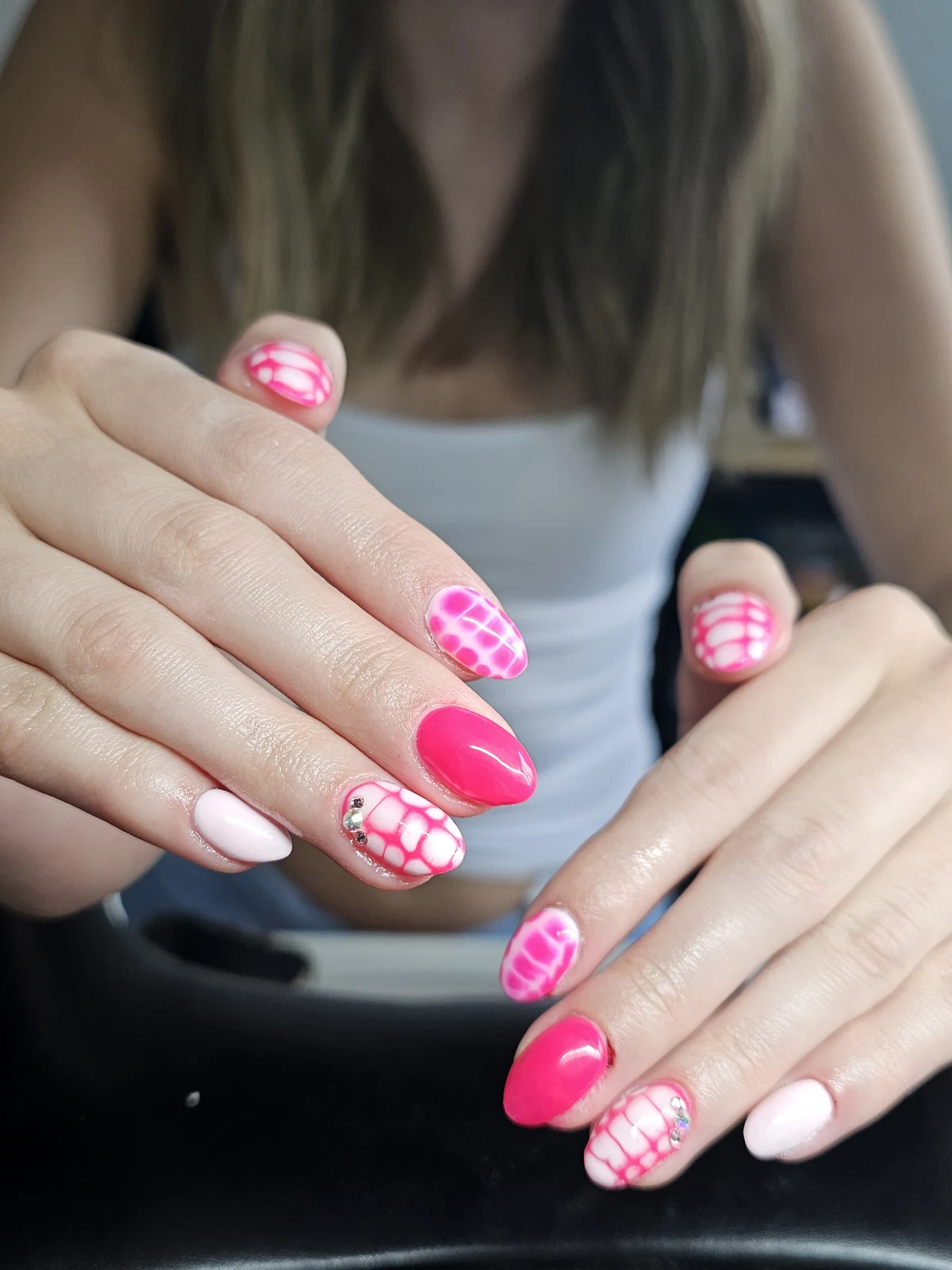 Hot pink and pale pink almond nails with bubble-like patterns and small crystal accents.