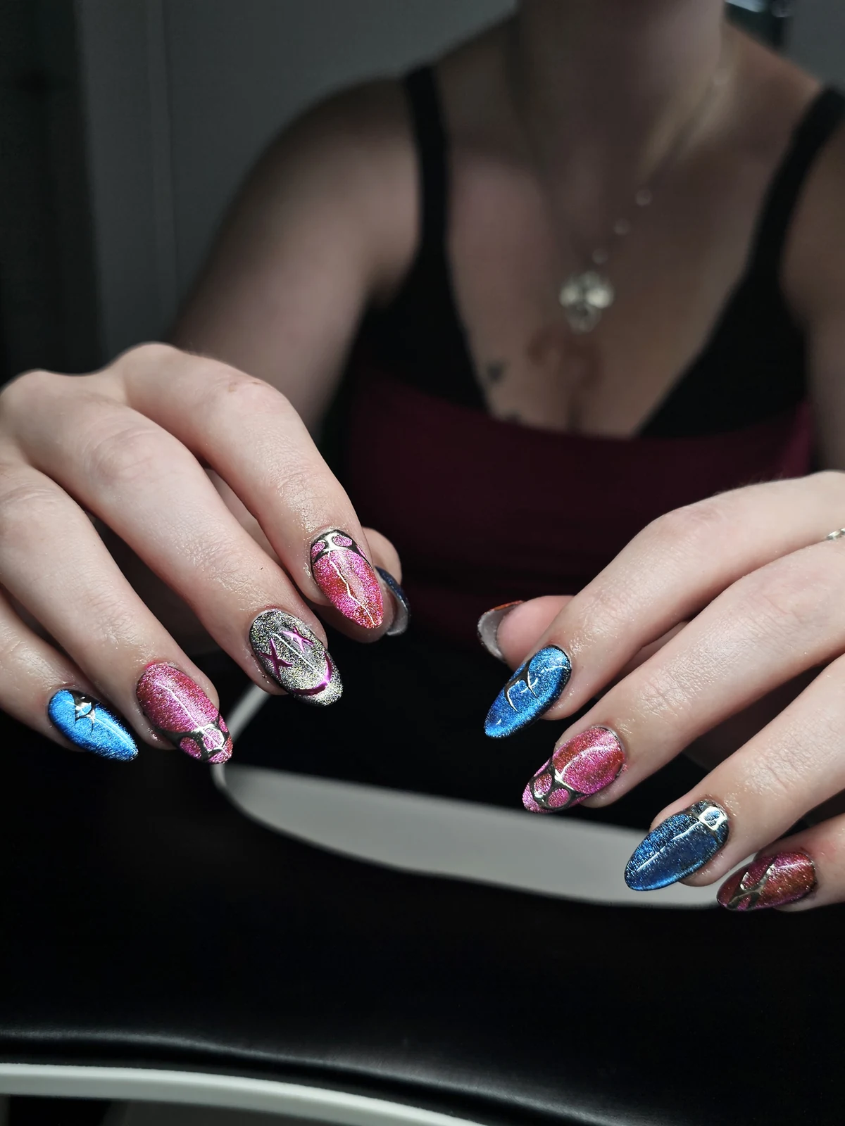 Shimmering pink, blue and silver almond nails with metallic outlines and star accents.