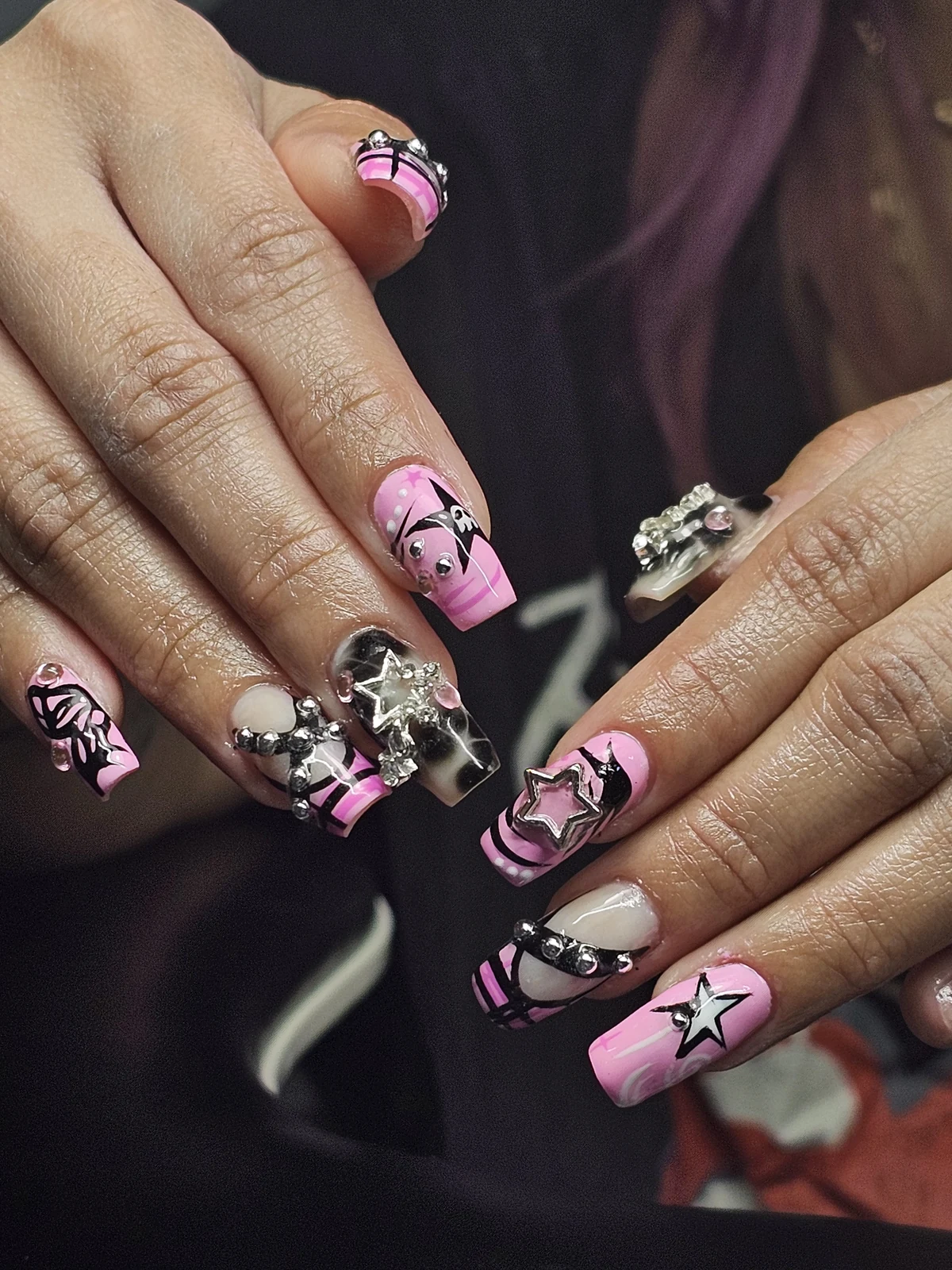 Long square pink and black nails with stars, bold lines, silver charms and crystal accents.