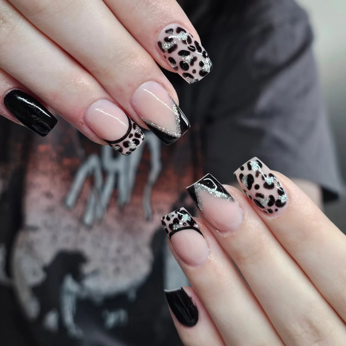 Nude nails with black French tips and leopard-print accents