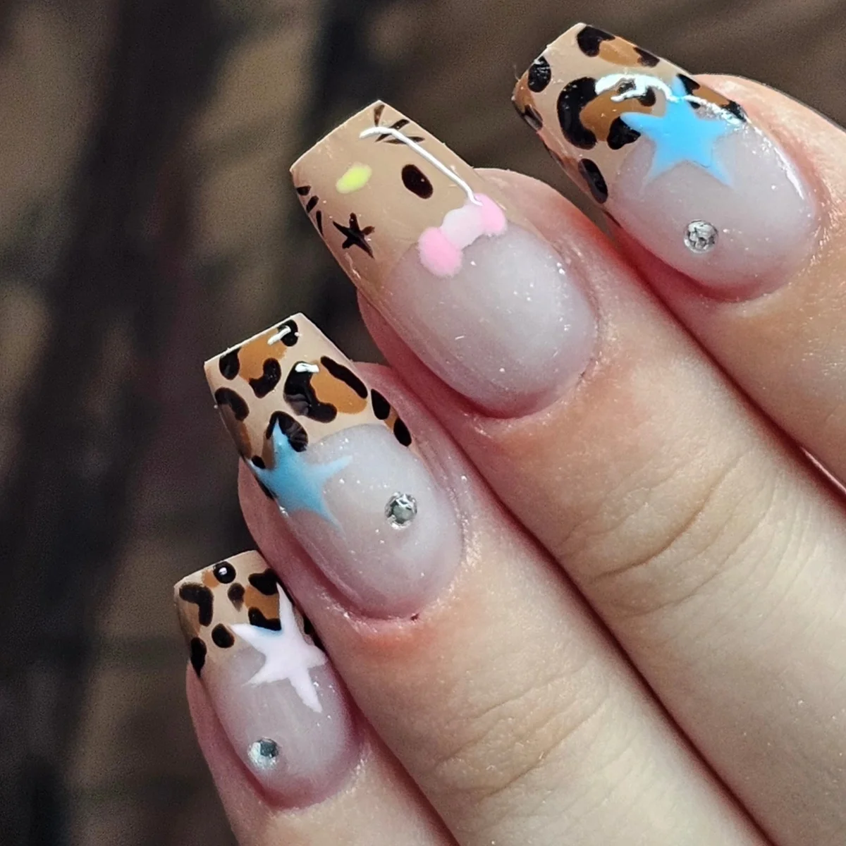 Nude nails with leopard tips, pastel bows and star accents