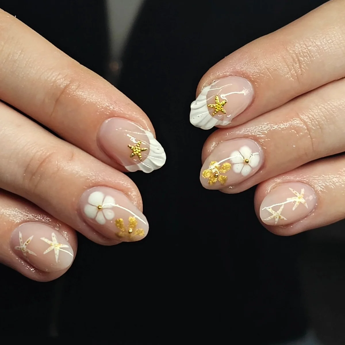 Nude almond nails with white flowers and small gold accents