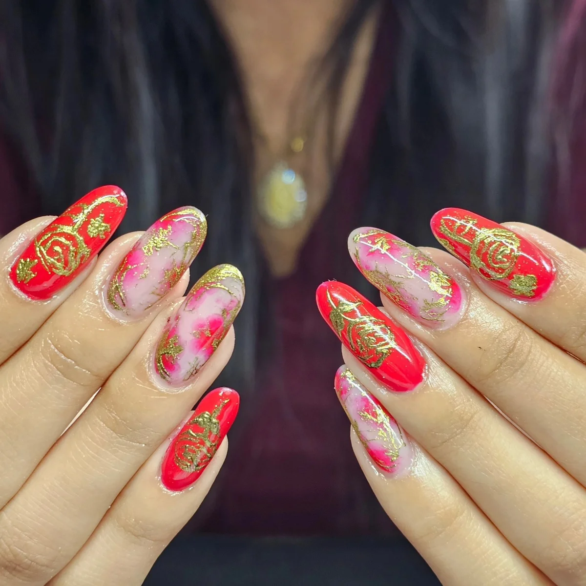 Long red and pink nails with gold and floral accents