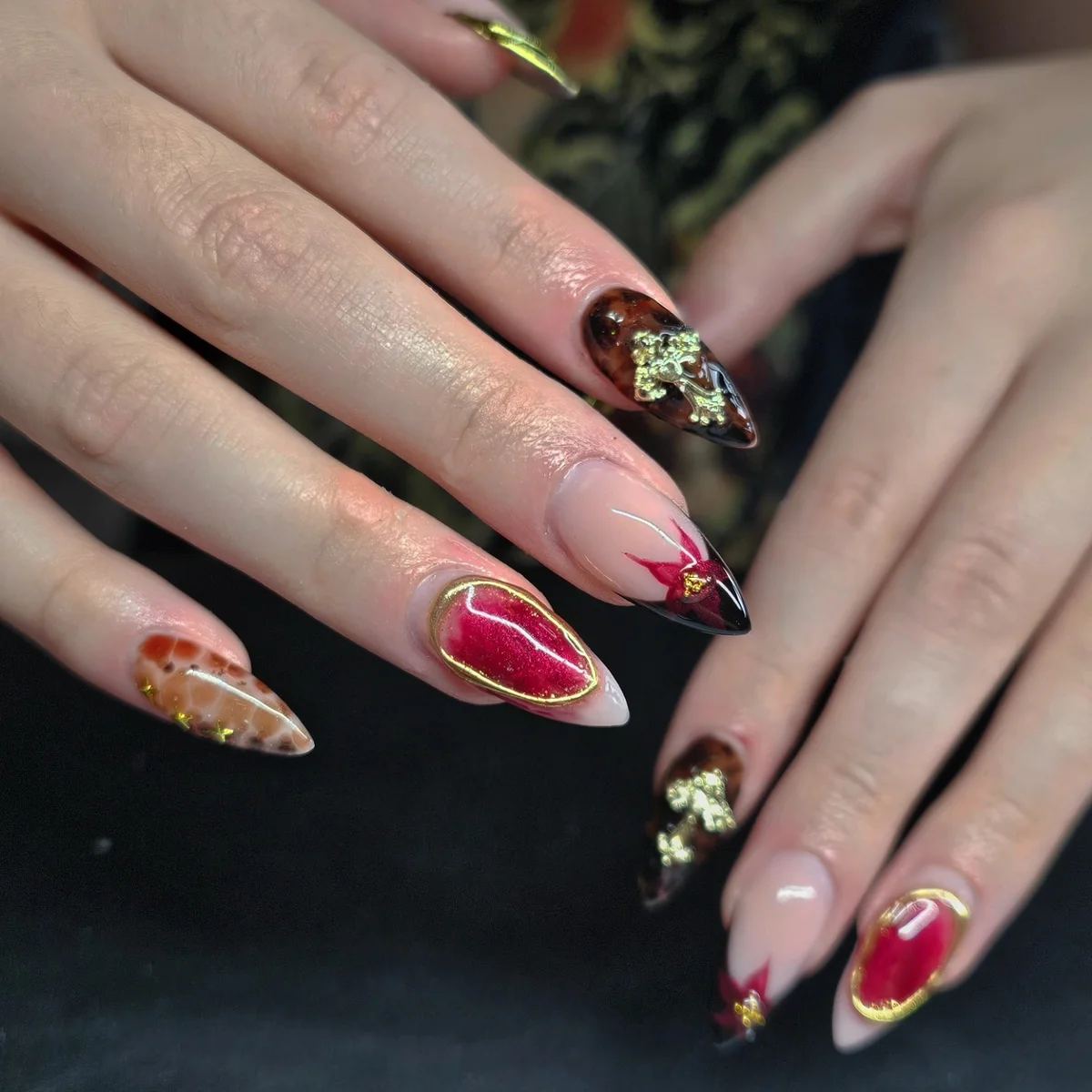 Nude nails with red, black and gold patterned tips