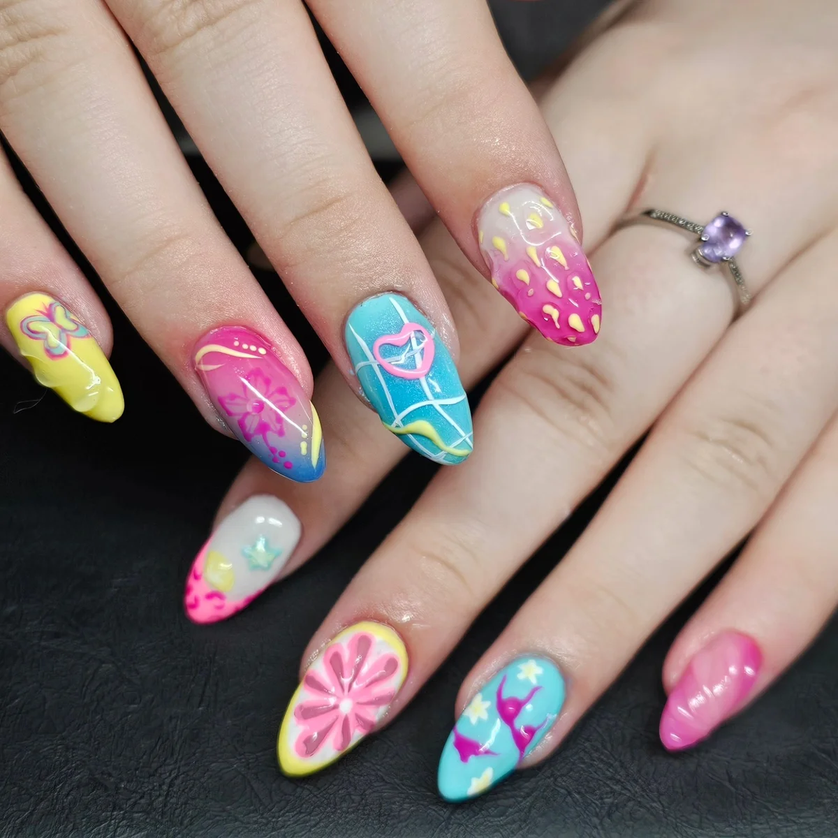 Colourful pink, turquoise and yellow nails with flowers, stars and abstract patterns.