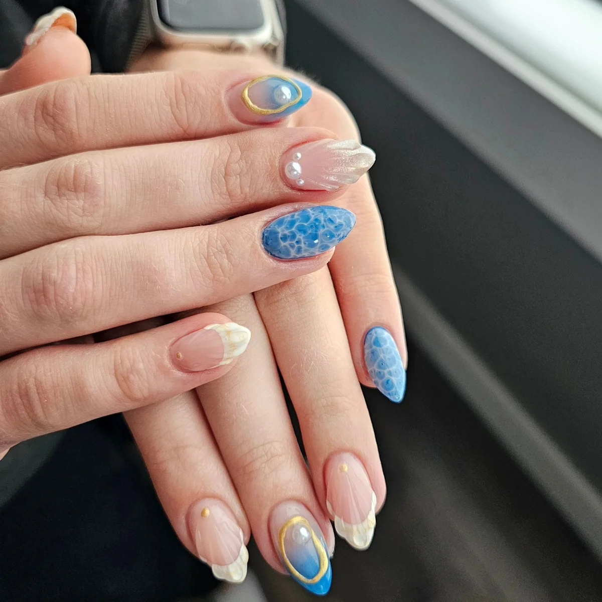 Nude and blue nails with gold outlines, textured blue accents and pale tips.