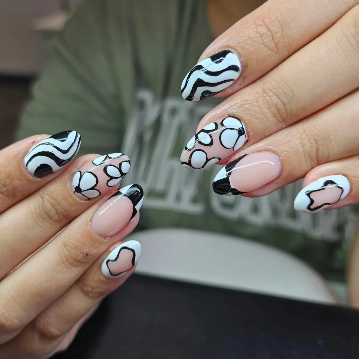 Black, white and nude nails with waves, dots and outlined shapes.