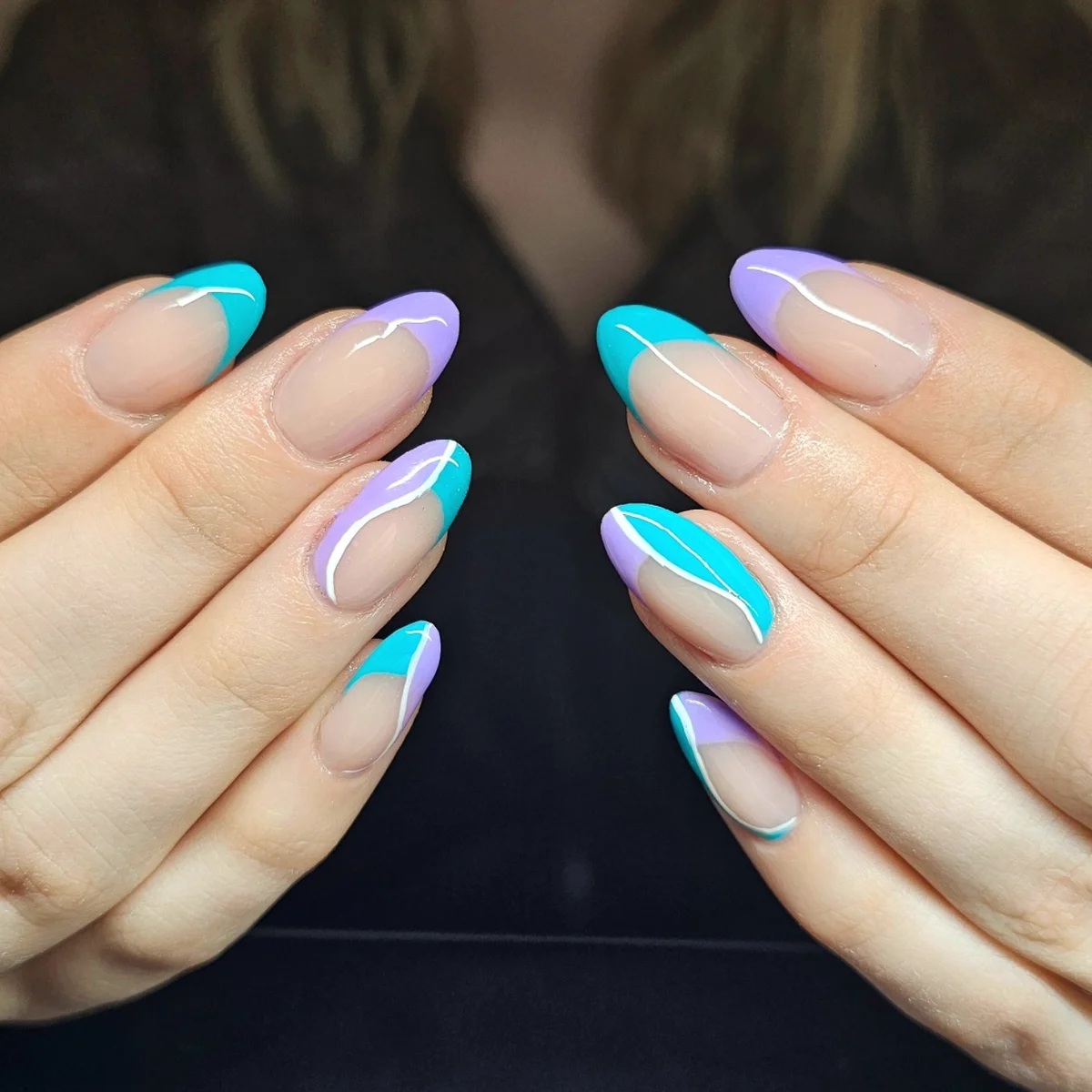 Nude almond nails with turquoise and lilac French tips.