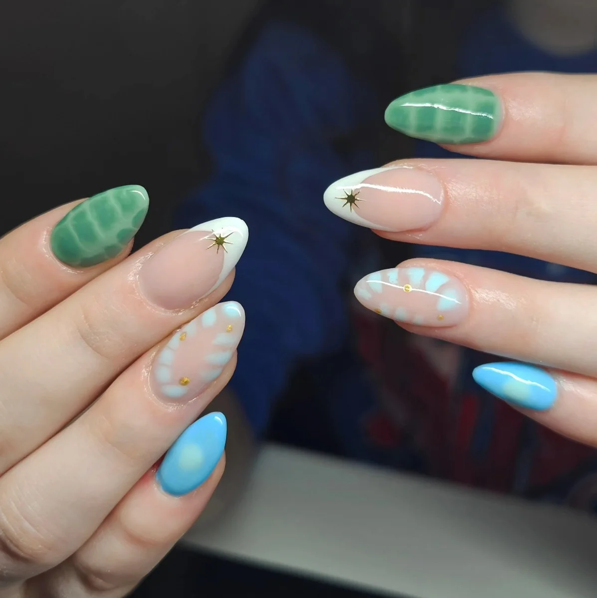 Blue, green and nude nails with pale tips, star accents and bubble patterns.