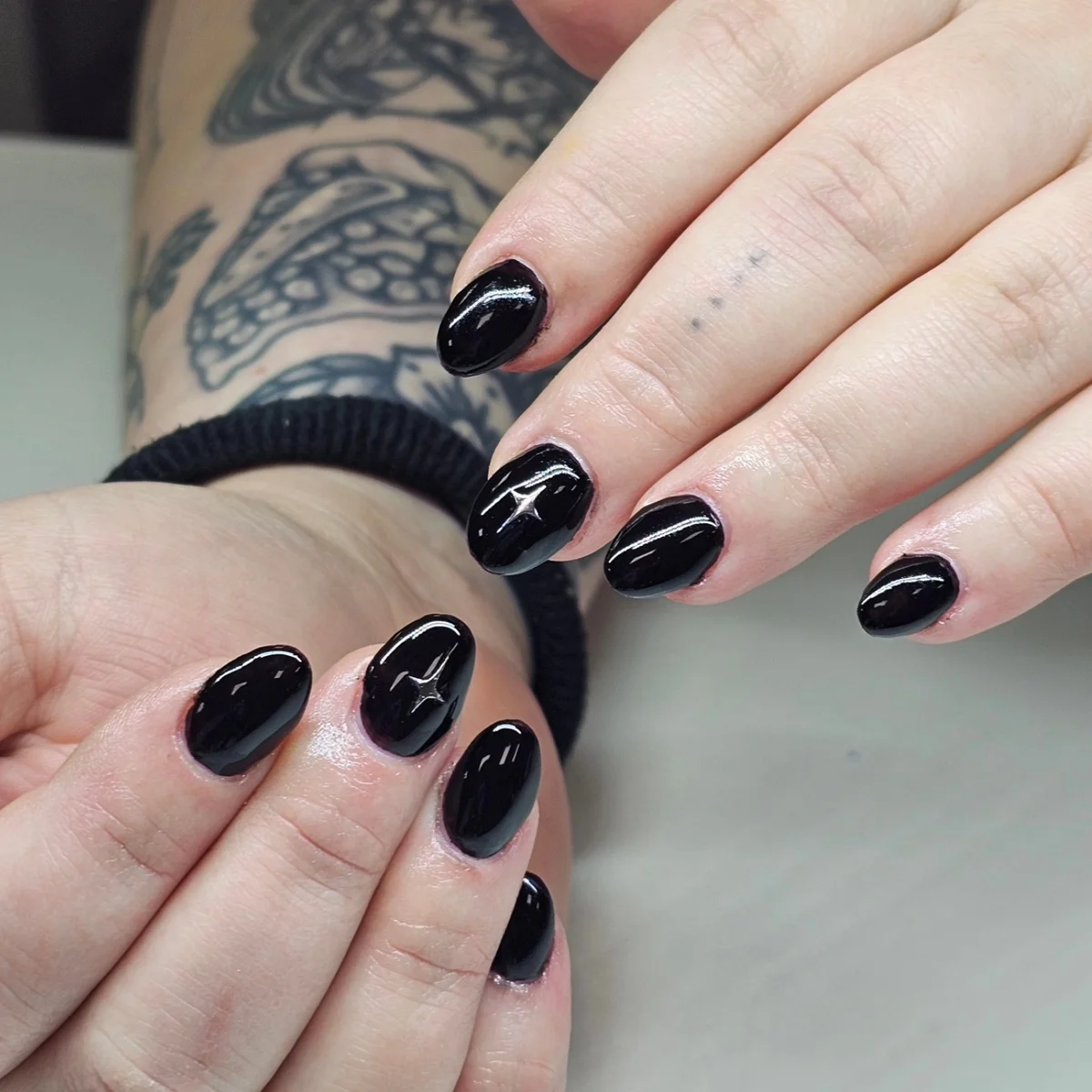 Glossy black almond nails with fine silver accents