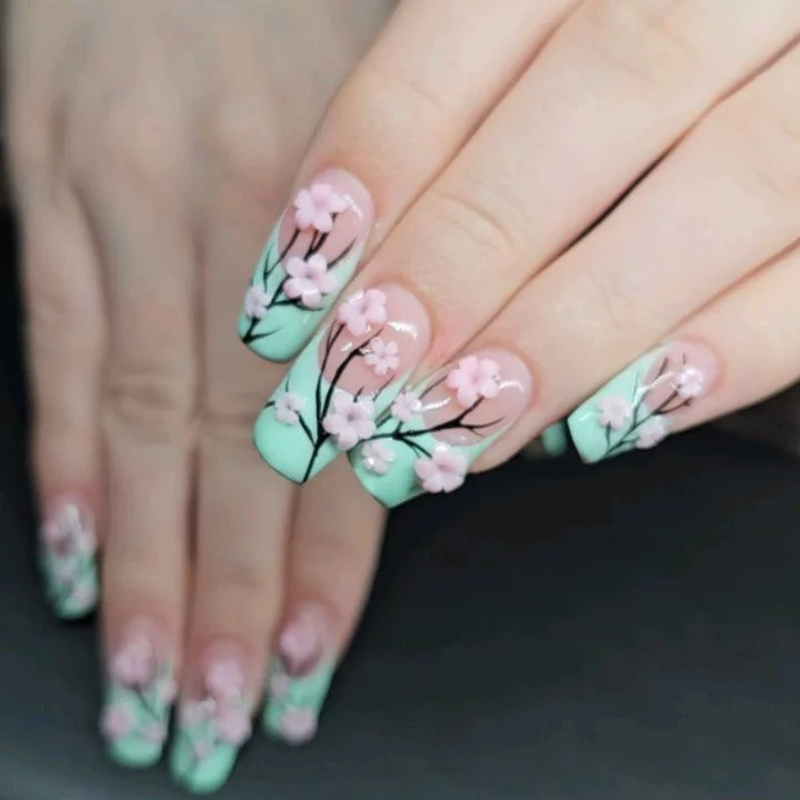 Nude nails with mint tips, pink flowers and fine black stems.