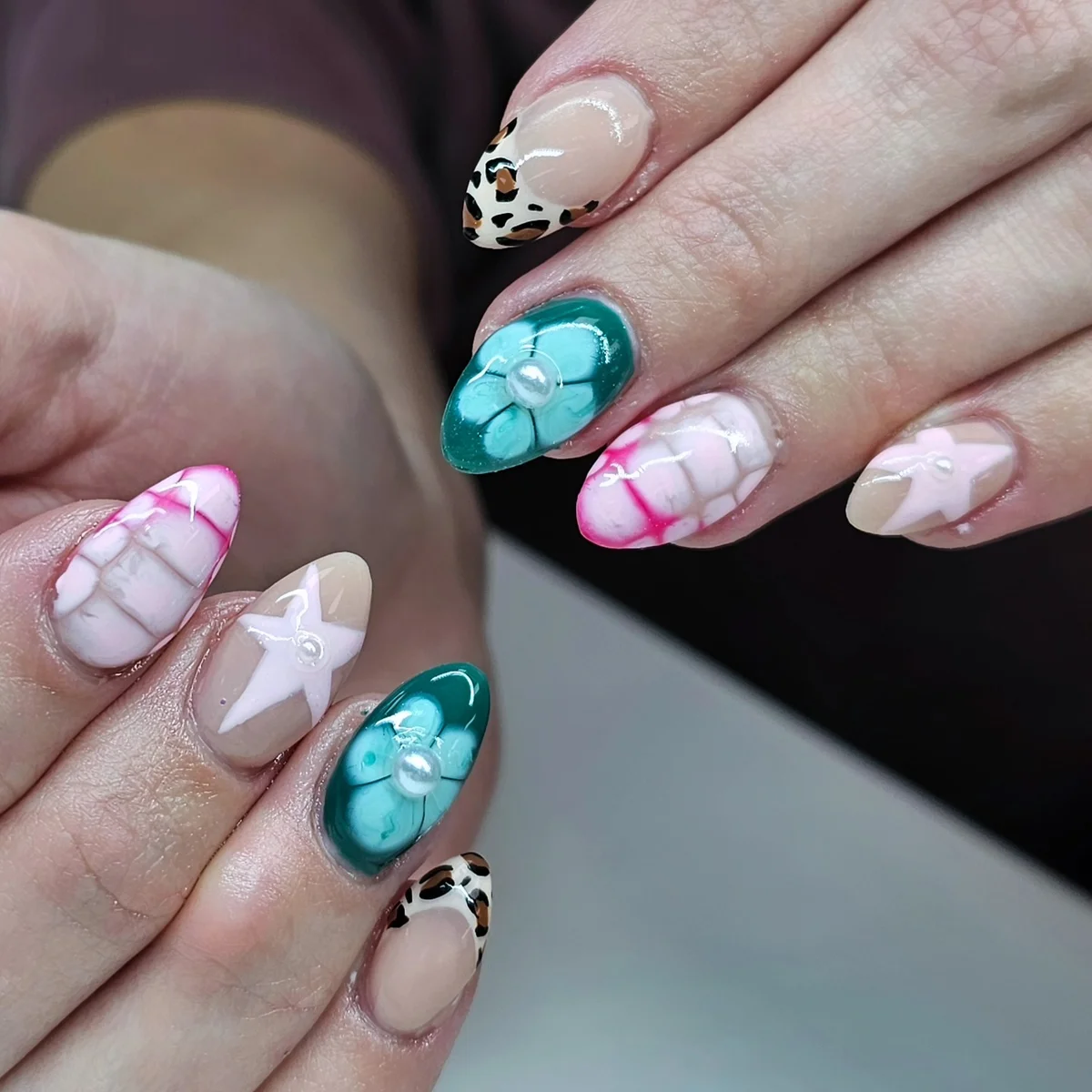 Nude nails with turquoise flowers, pale stars, pink bubble patterns and spotted tips.